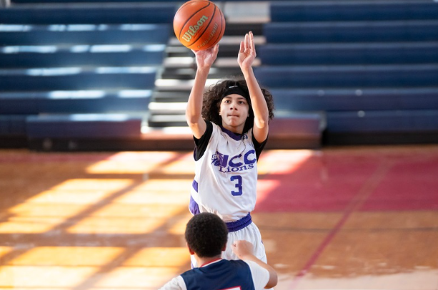Young girl in a basketball jersey shooting a basketball during a game or practice in a gymnasium.