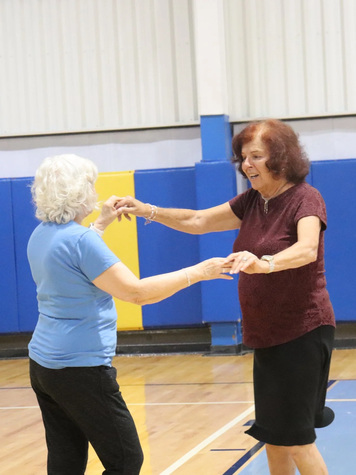 Two women are dancing together in a gymnasium.