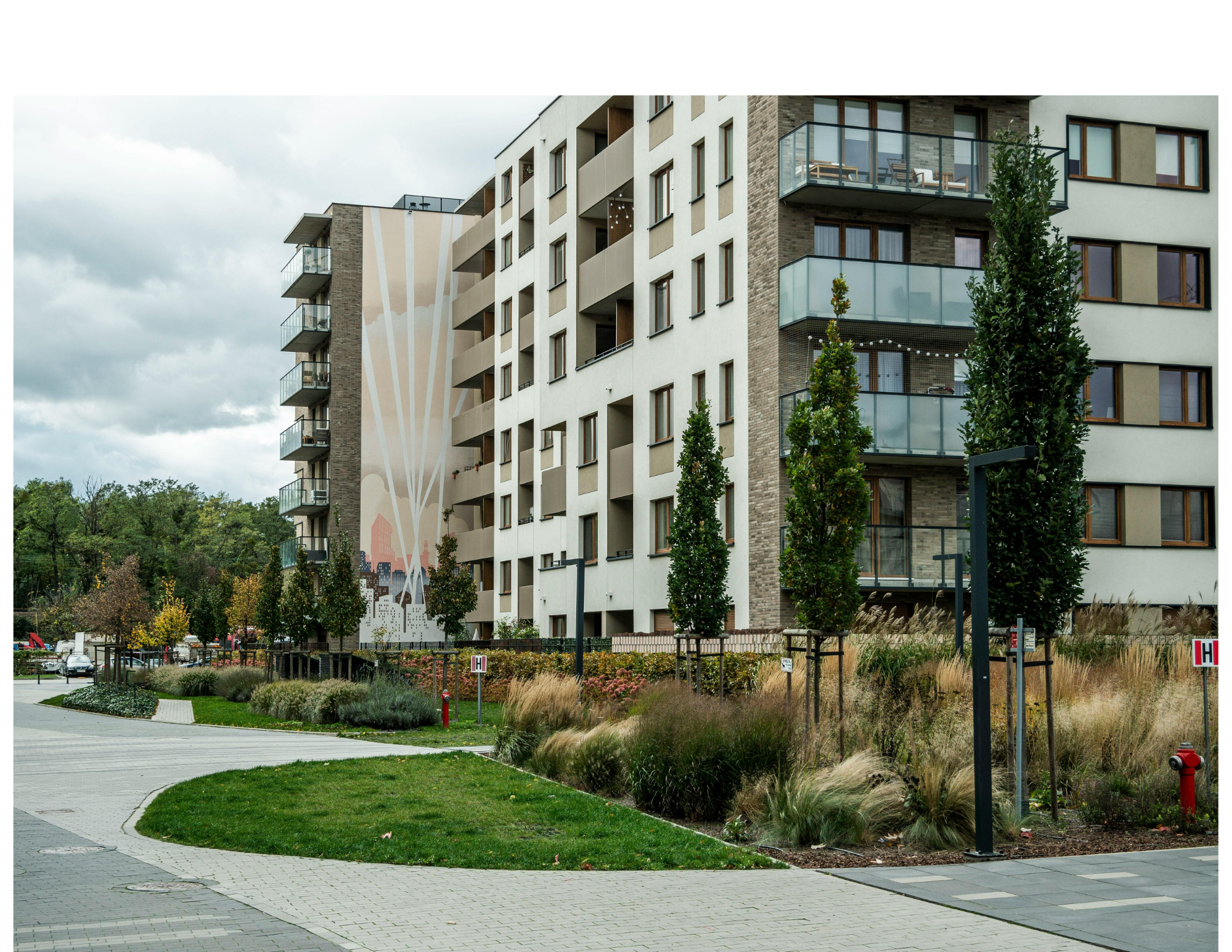Modern residential apartment building with balconies, trees, and landscaped areas.