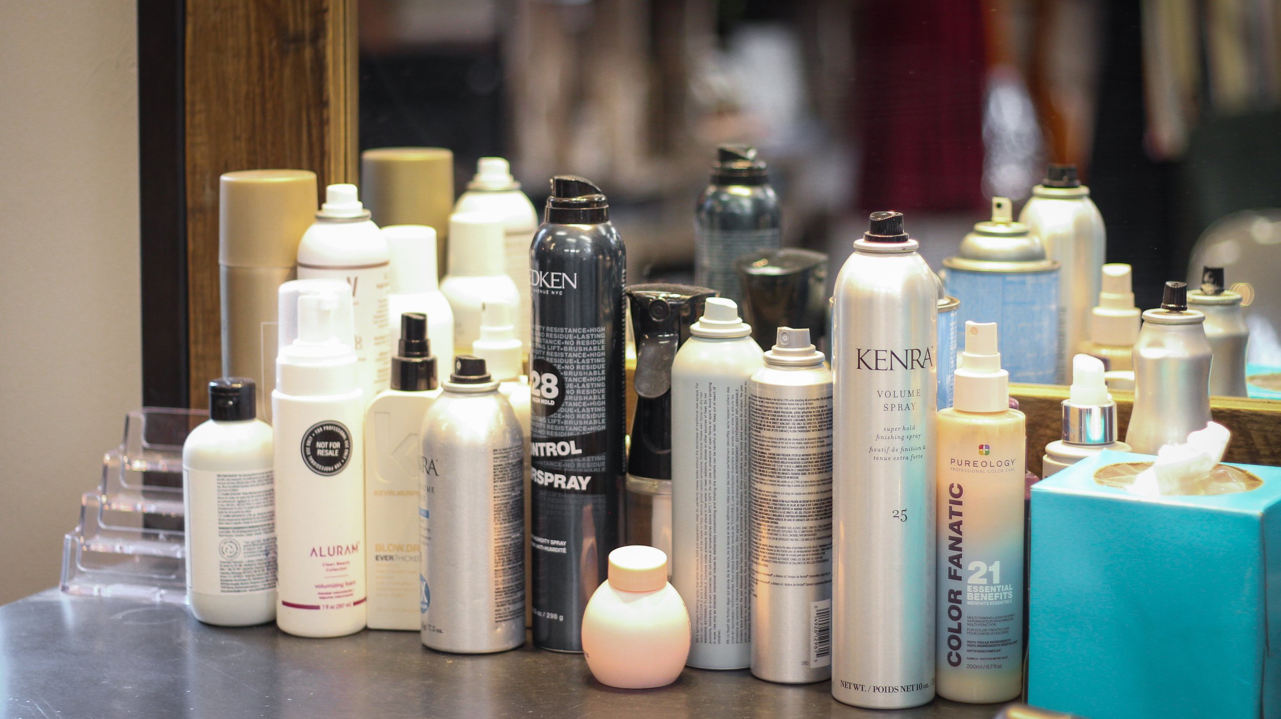 A hair stylist station with haircare products lined up in front of a mirror.