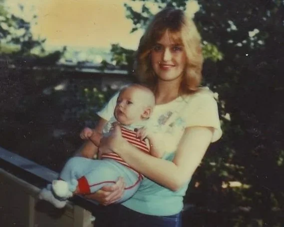 Coach Brice Williams (baby / childhood photo)  with his mother with shoulder-length wavy hair holding a baby outdoors during daytime. Brice Williams ; Brice A. Williams. 