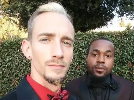 Two classy, stunning, handsome men dressed in formal attire, standing outdoors near a hedge. Brice Williams ; Brice A. Williams ; Coach Brice Williams. 
