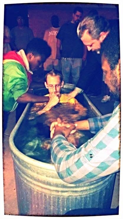 A group of people, are gathered around a baptismal pool during a religious baptism ceremony for the international Christian Church, with others observing in the background. Coach Brice Williams ; Brice Williams , Brice A. Williams.  