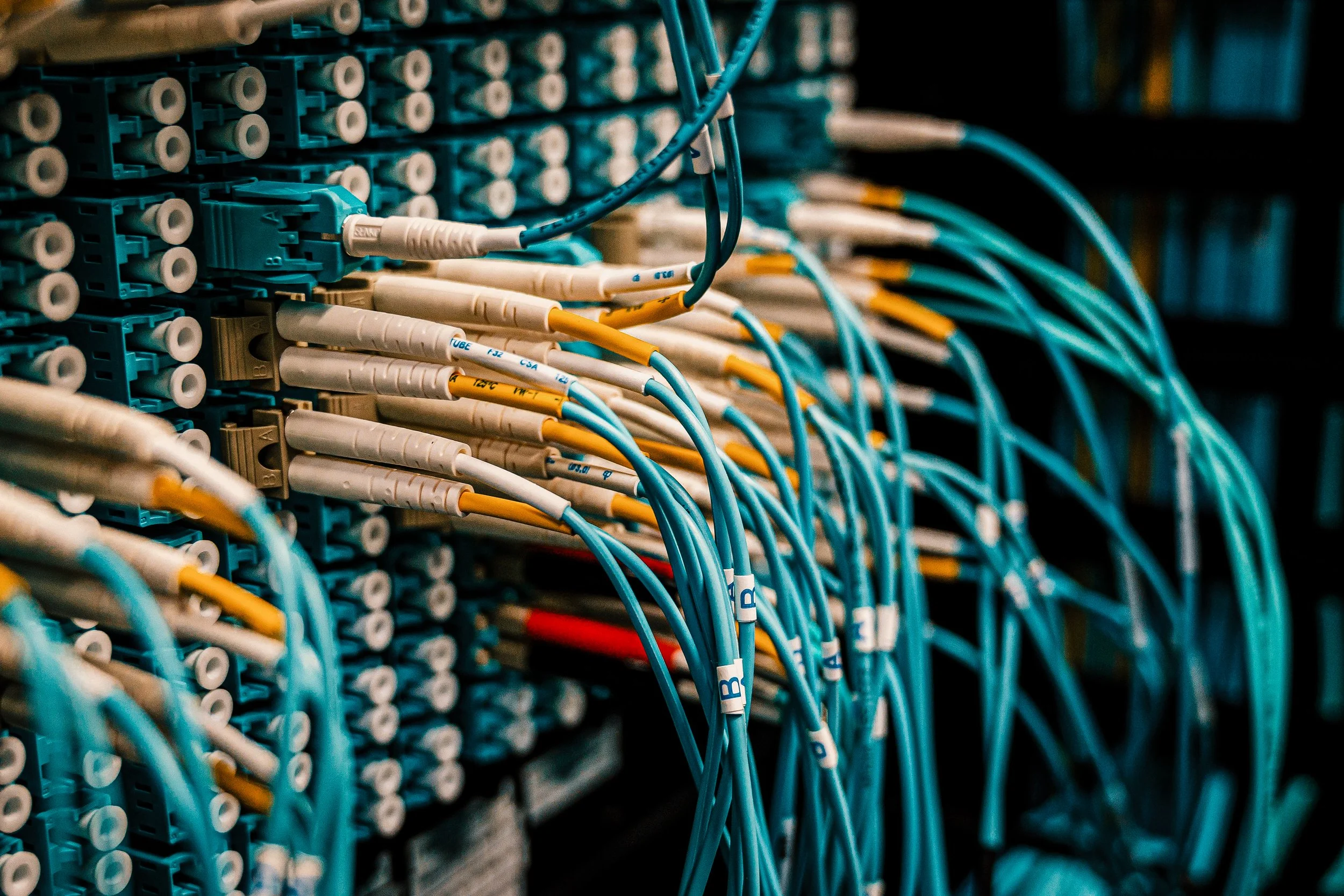 A server rack with multiple network cables plugged into blue ports, organized with white and yellow labels.
