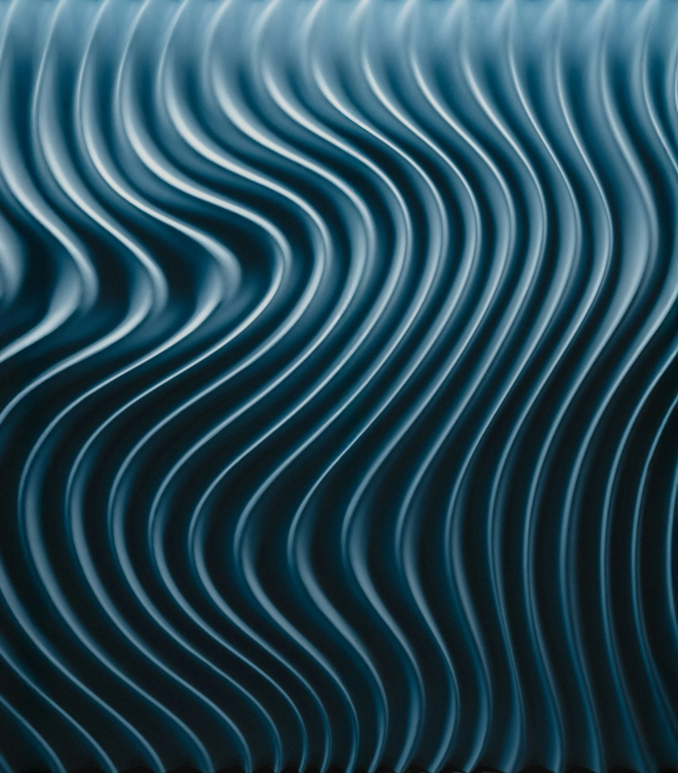 Close-up of a dark blue metallic surface with curved, parallel ridges creating a pattern of waves.