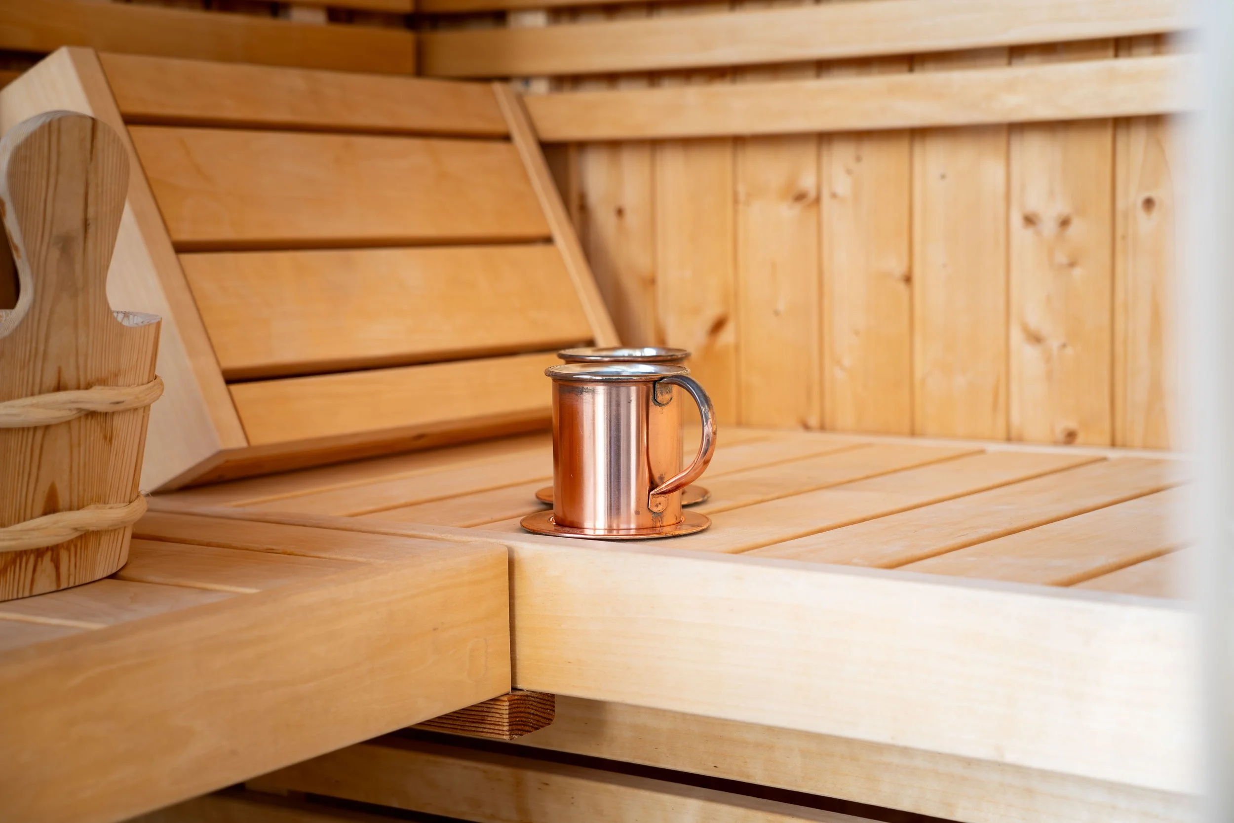 Close-up of a copper cup on a wooden surface with a wooden panel background.