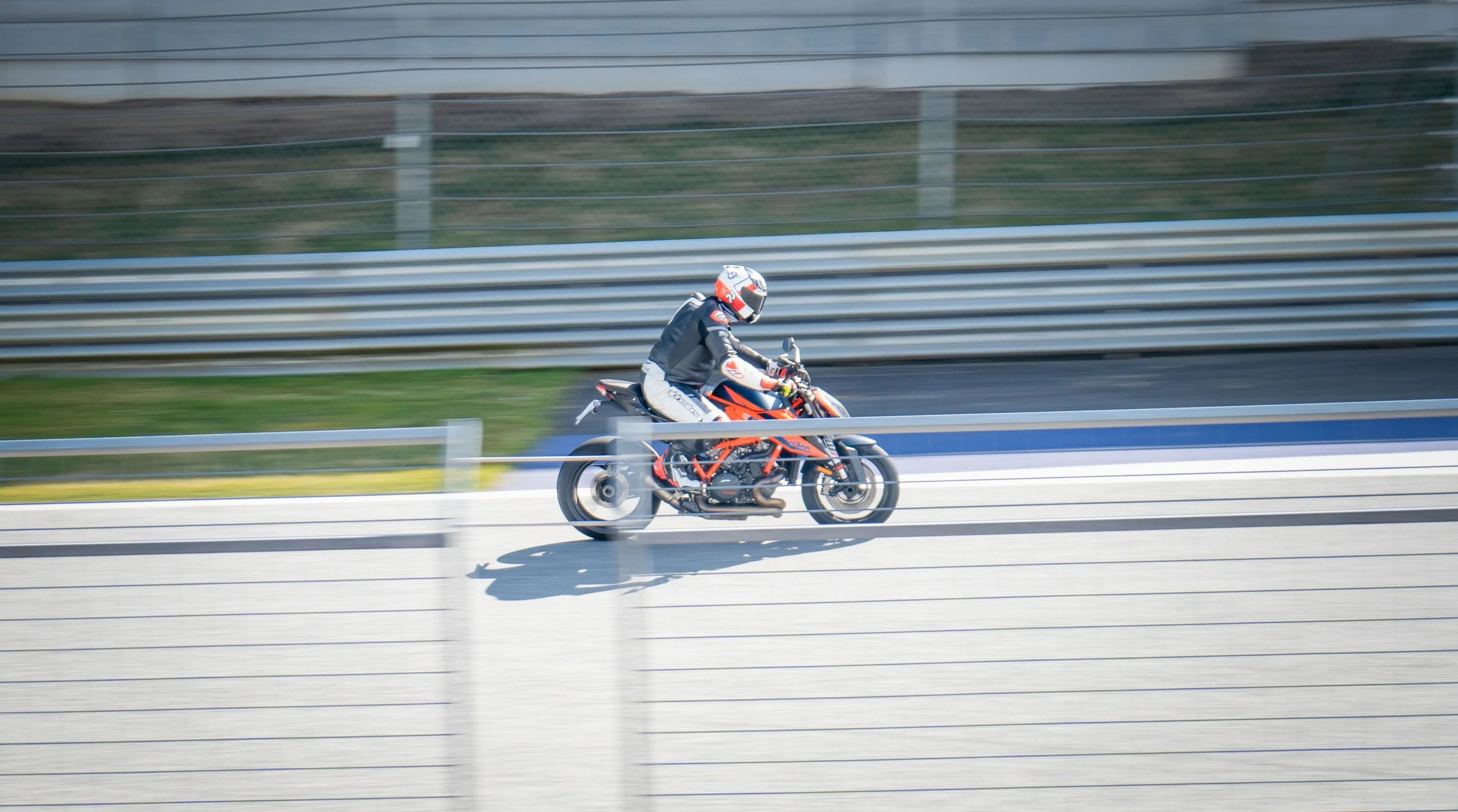 A motorcyclist wearing a helmet and safety gear riding on a racetrack, with motion blur indicating high speed.