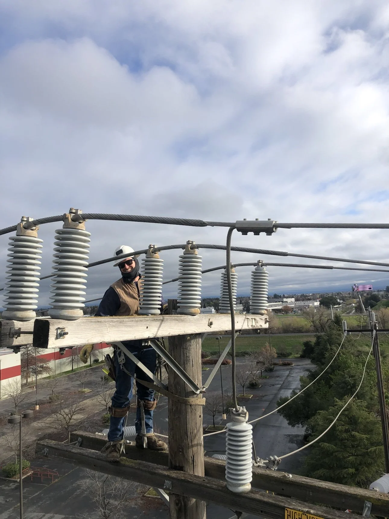 Elevate Utilities lineman on a crossarm among insulators performing overhead line work