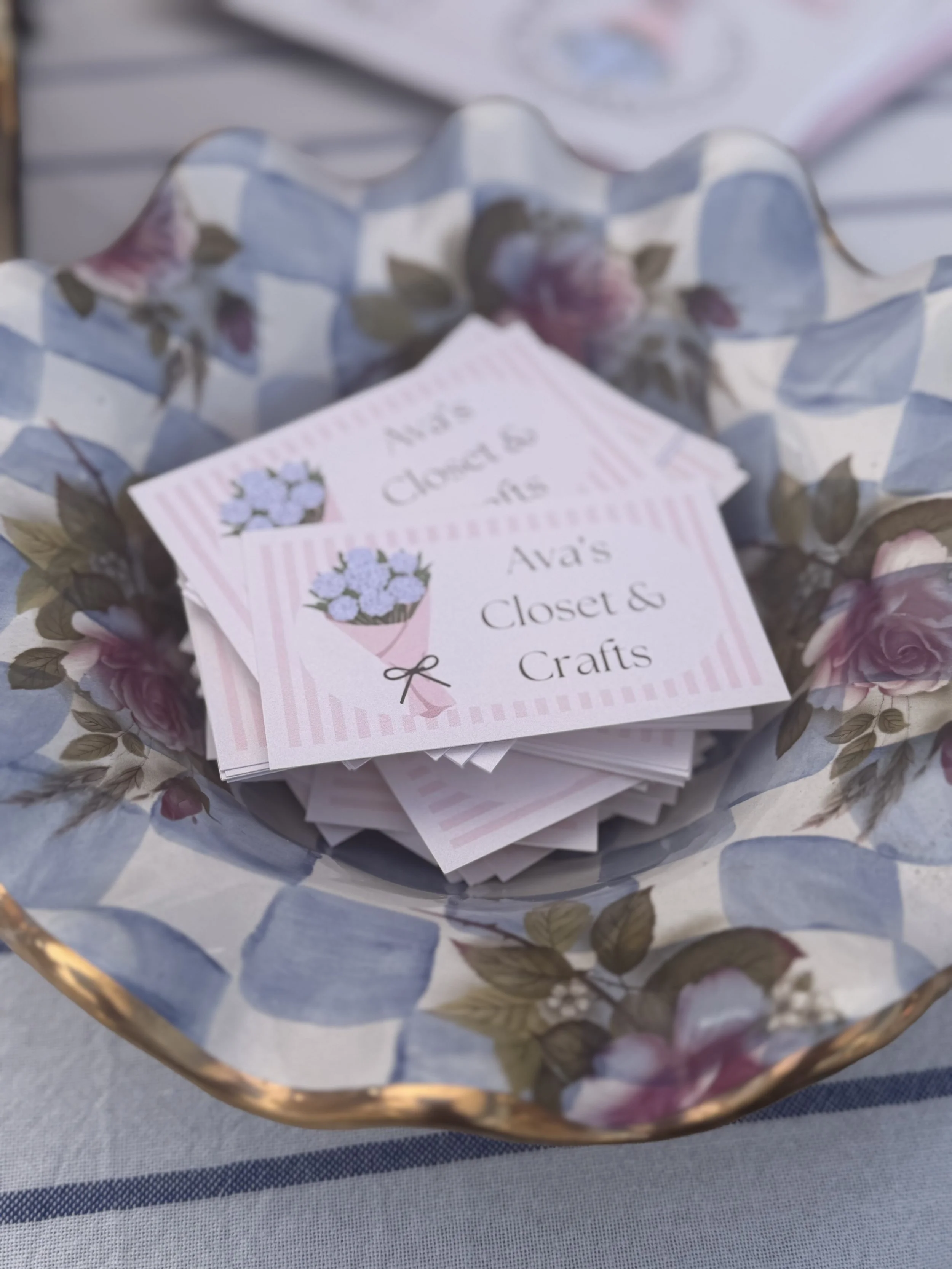 A basket lined with floral-patterned paper containing small pink cards with a floral design and text about an event or business.