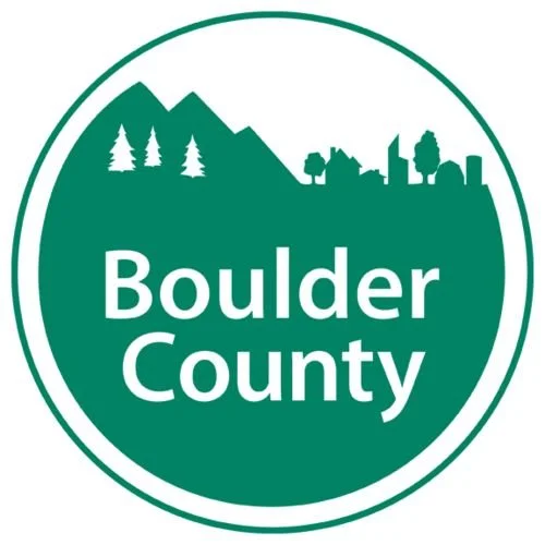 Logo for Boulder County featuring mountains, trees, and a city skyline in green and white.