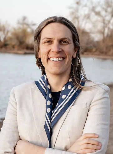 Smiling woman with long brown hair and a blue polka dot scarf