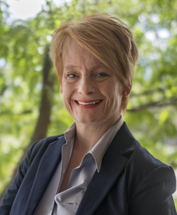 Smiling woman with strawberry blonde hair and a navy jacket