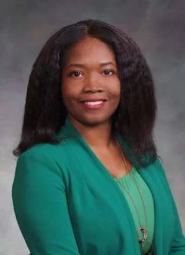 smiling woman with black hair and a green suit