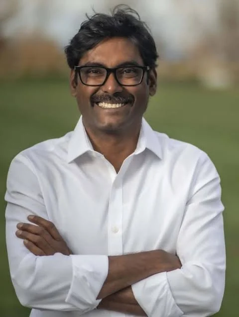Smiling man with dark hair and mustache and glasses.