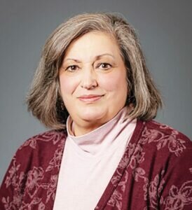 woman with shoulder length hair and a turtlneck and blazer