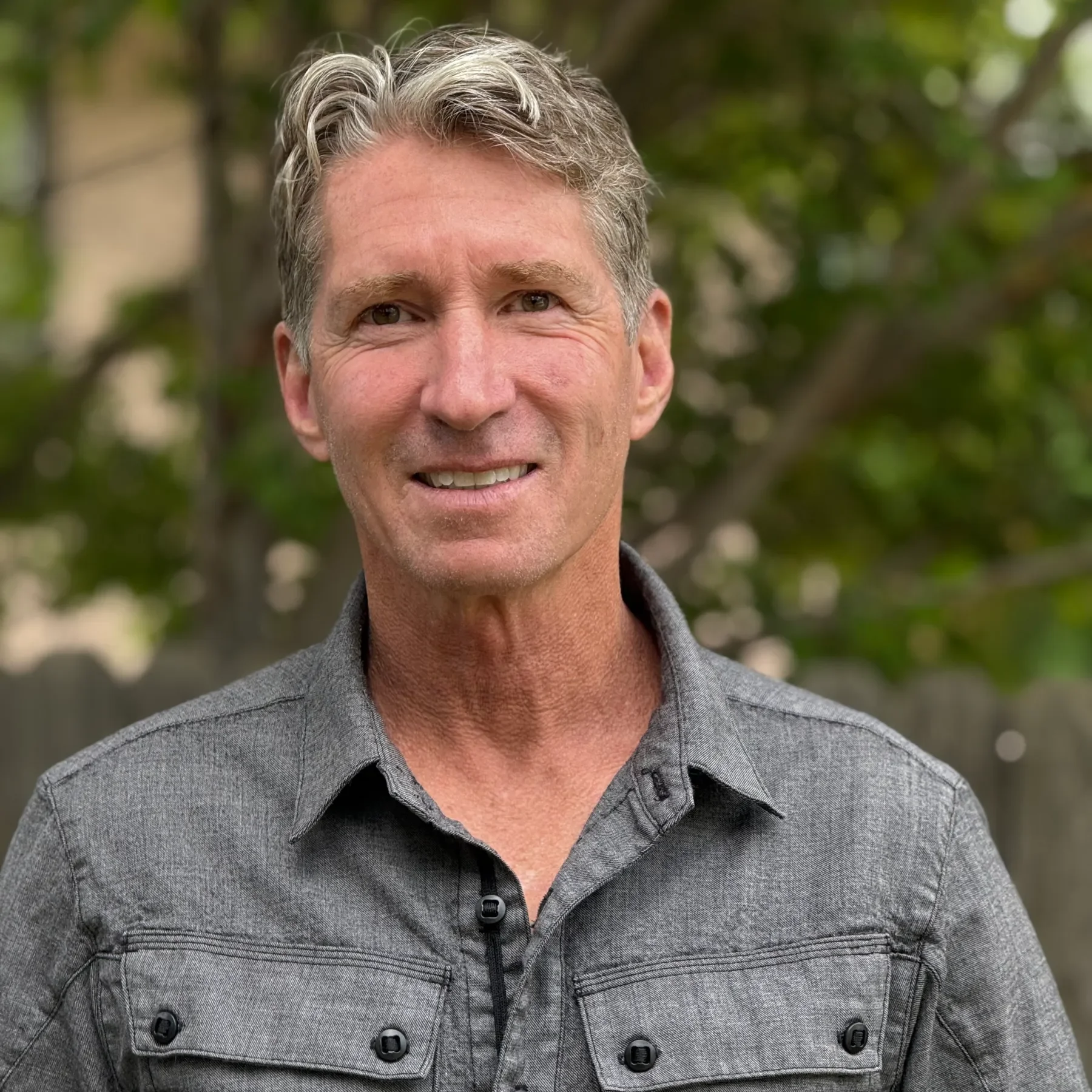 smiling man in a grey button down shirt