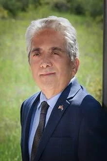smiling man with gray hair and a blue suit