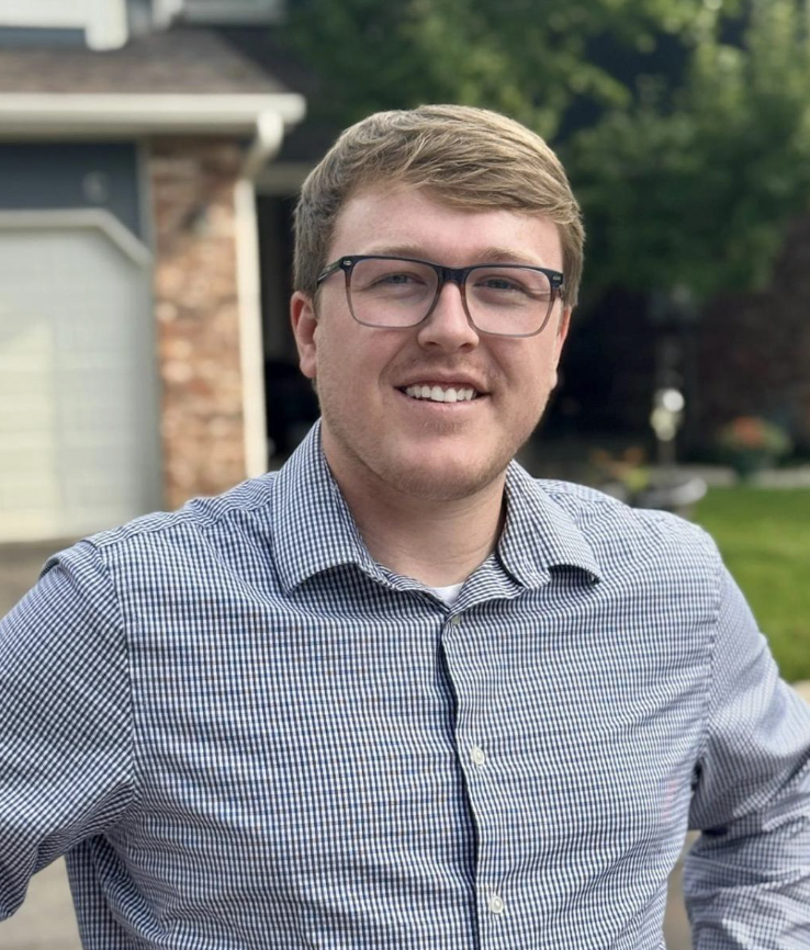 A smiling man outside wearing a button down shirt