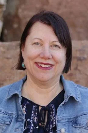 Smiling woman with short brown hair and a denim jacket
