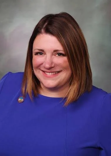 Smiling woman with brown hair and a blue dress