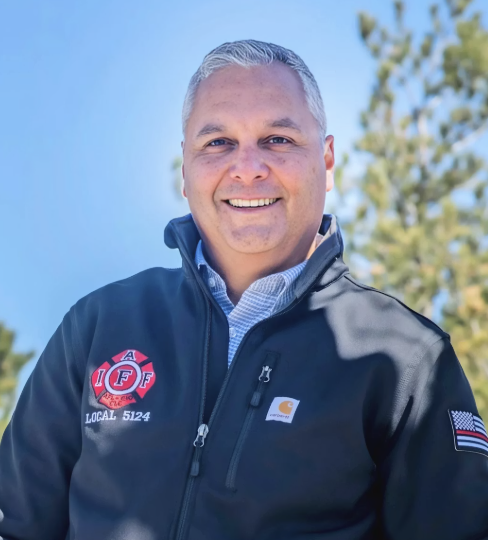Smiling man with gray hair and a firefighter jacket