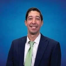 Smiling man with brown hair and green tie