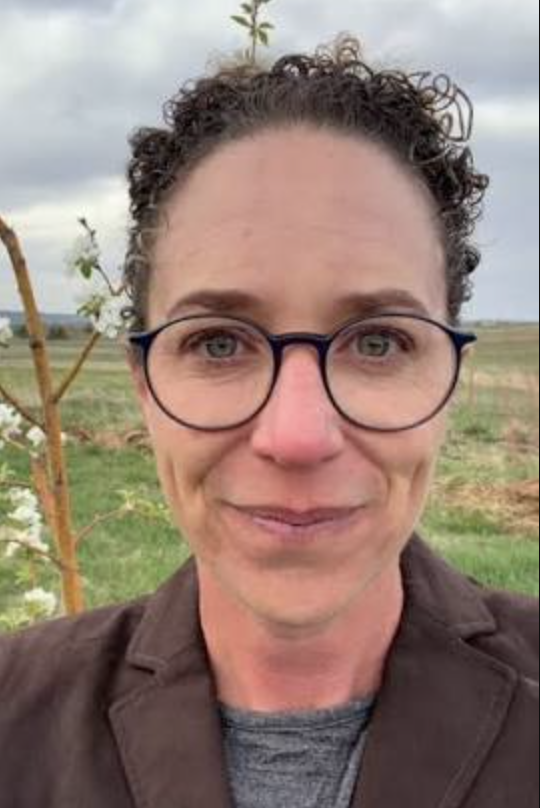 smiling woman with curly hair and glasses