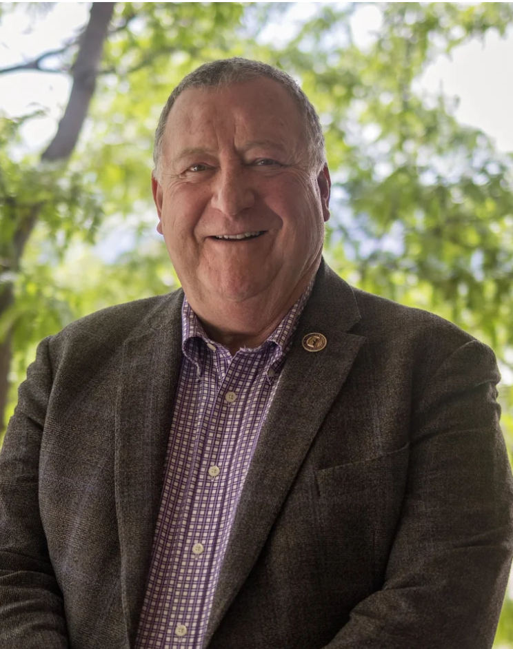 Smiling man in a brown suit and plaid shirt