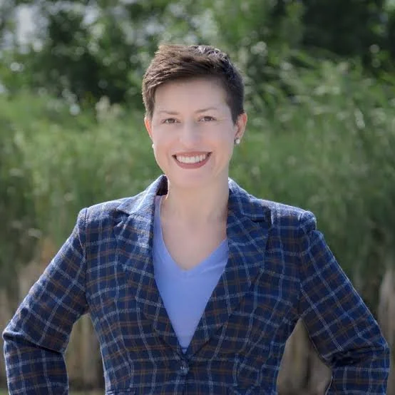 smiling woman with short brown hair and a blue plaid jacket