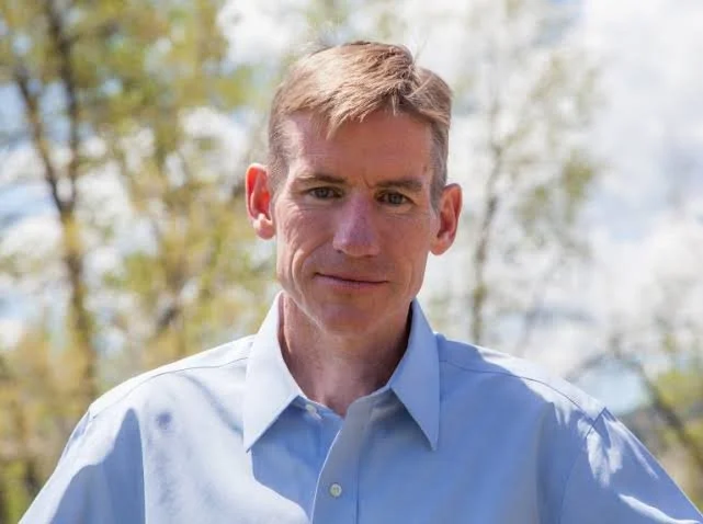 Man with sandy hair and a button down blue shirt.