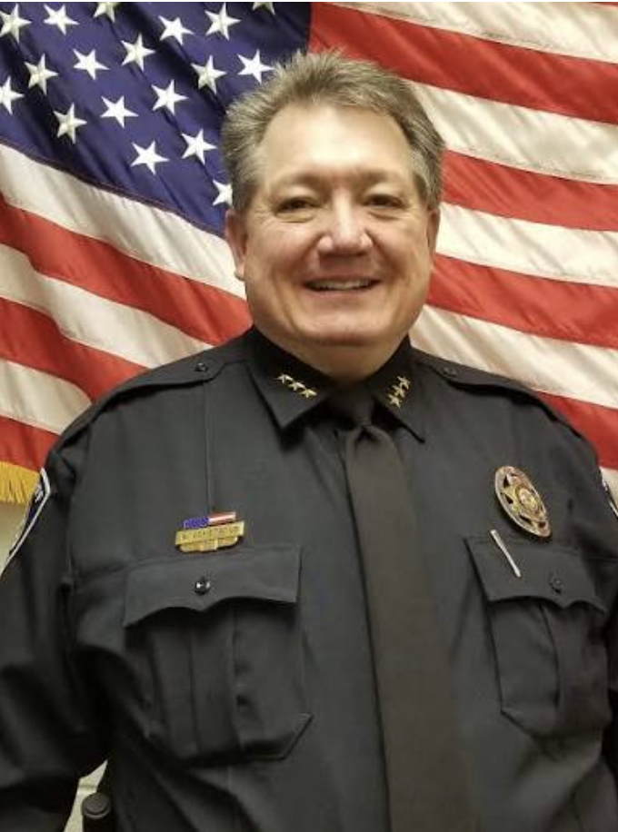 Smiling man in sheriff uniform in front of US flag