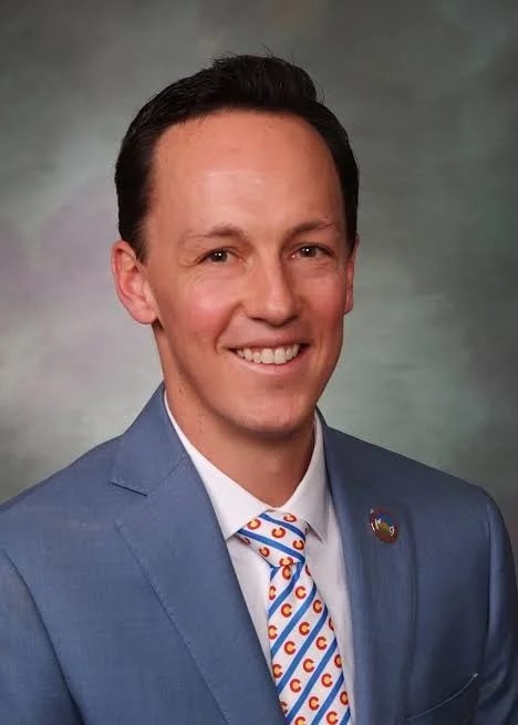 Smiling man with brown hair in a blue suit