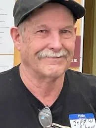 smiling man with a white mustache and black shirt