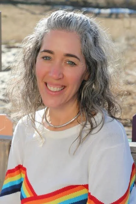 Smiling woman with silver hair and a rainbow shirt