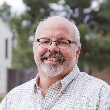 Smiling man with a white beard and glasses