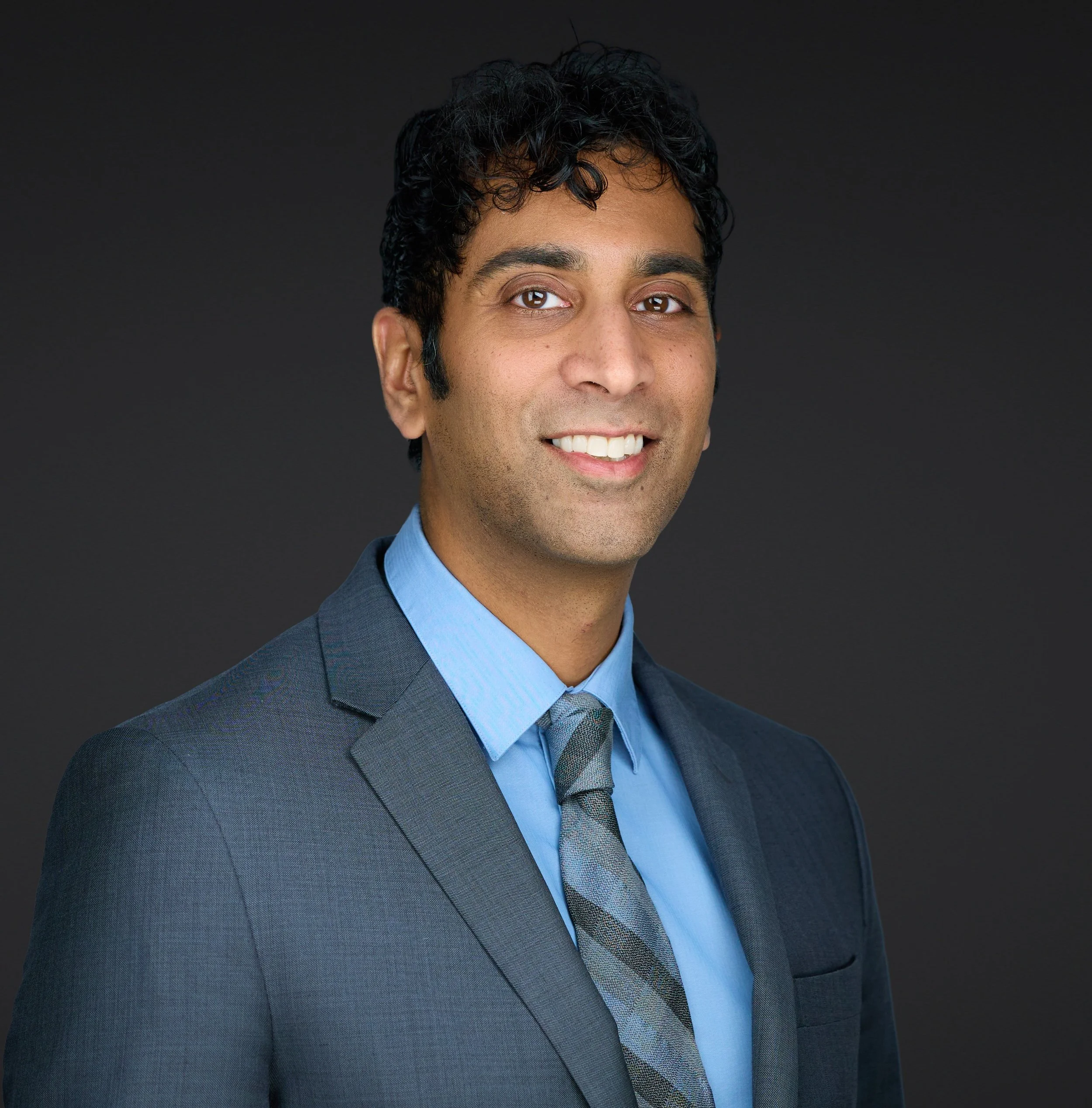 Smiling man with dark hair and a blue suit