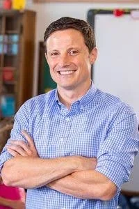 Smiling man with brown hair and arms crossed