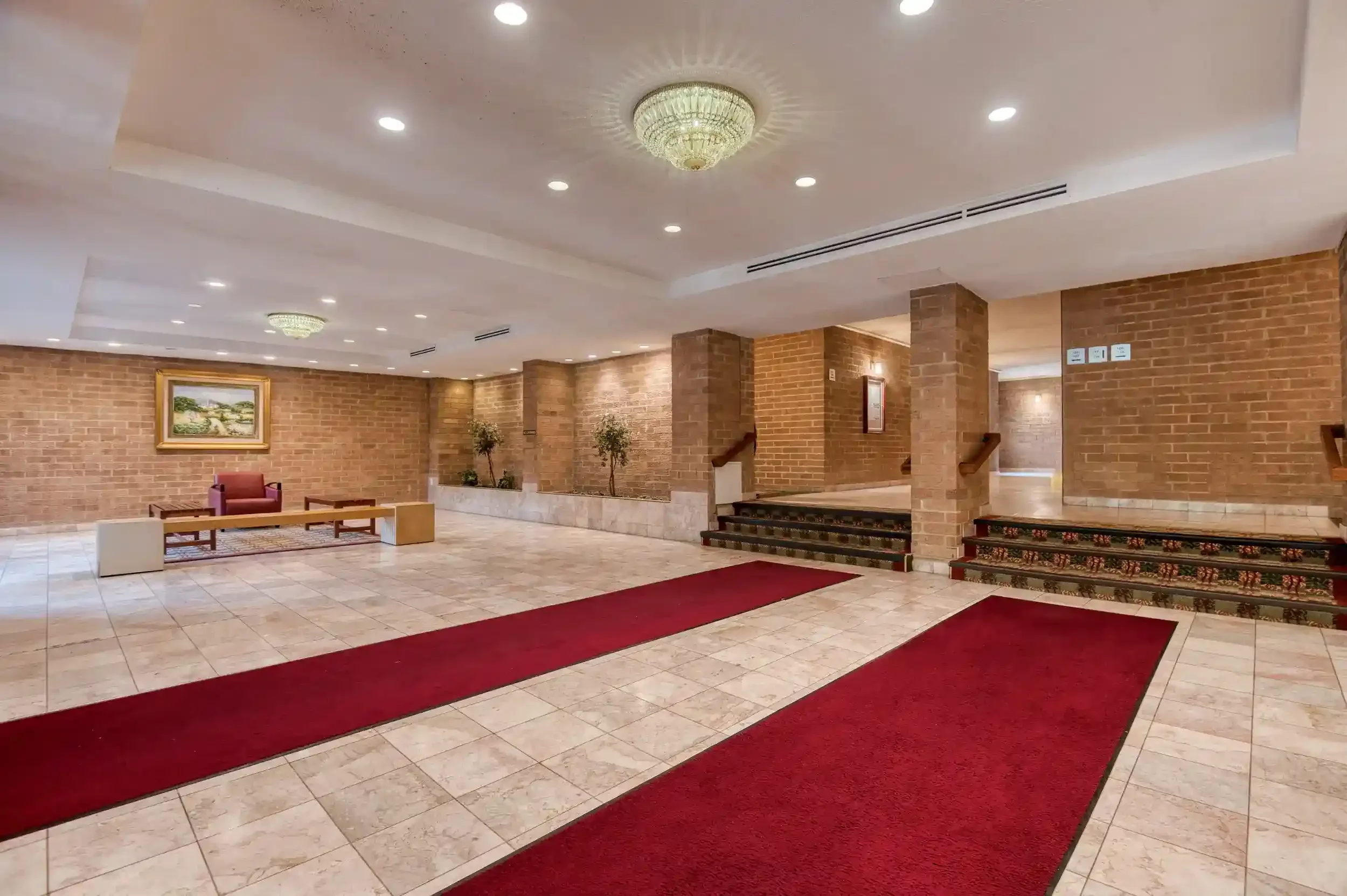 Lobby (View 1) – The Carlyn’s lobby is accented with brick walls and a red runner from the entrance.
