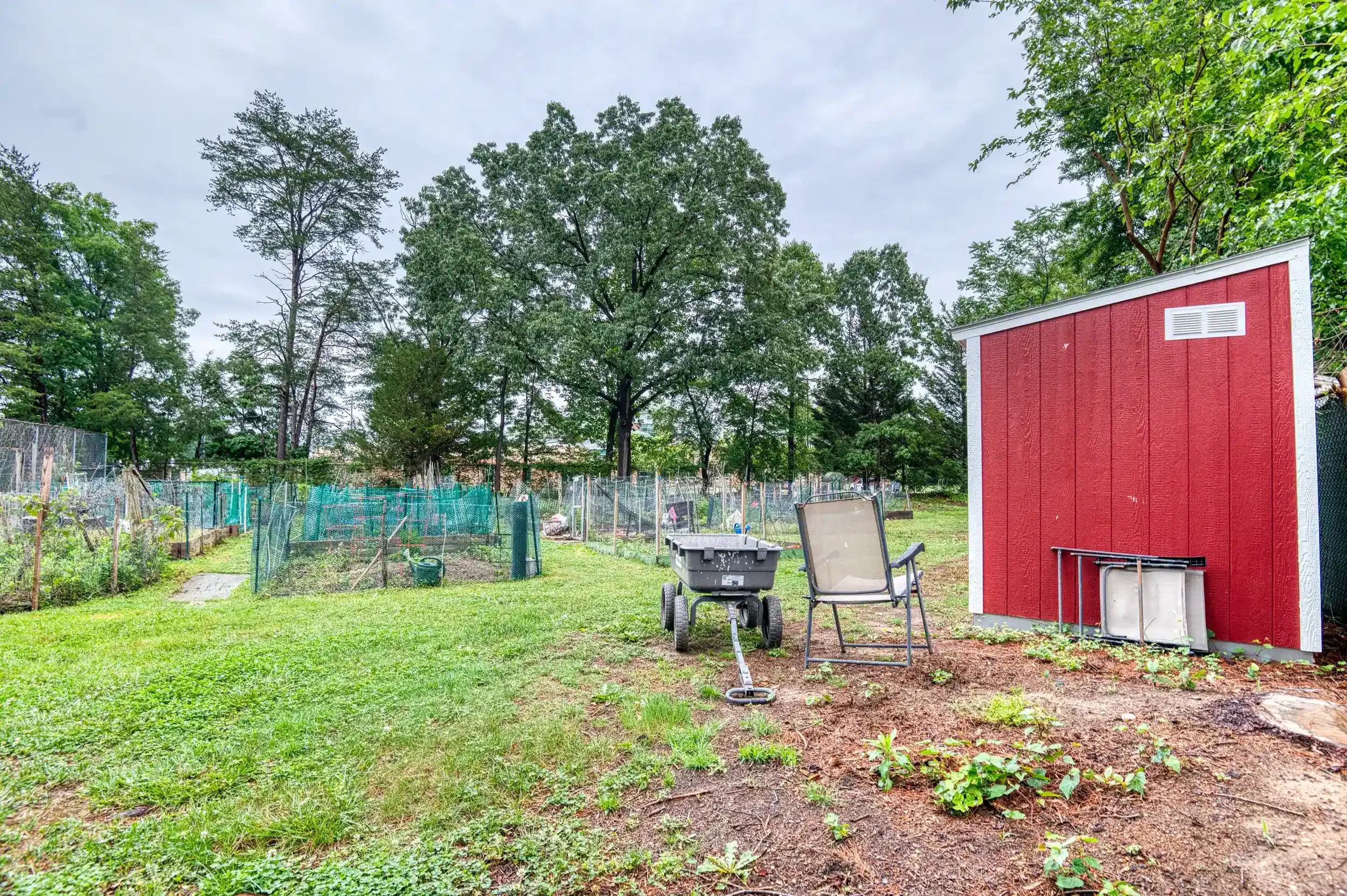 Community Garden (View 2) – A storage shed and lawn area support residents working in their garden beds.
