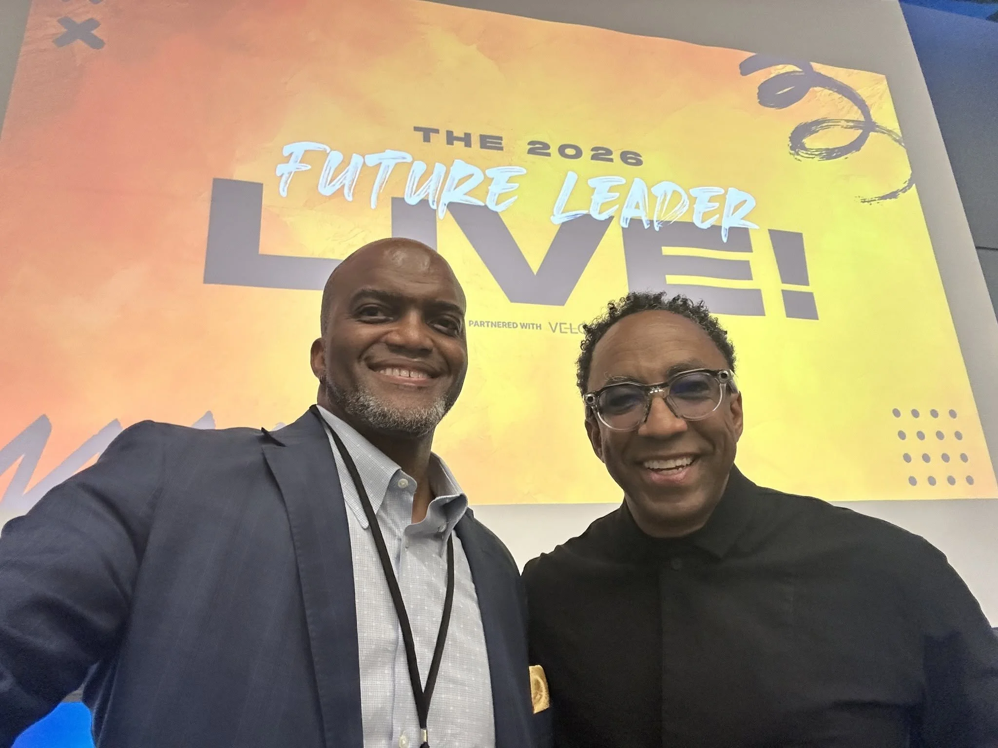 Two men, one being Toby Brazwell, smiling at the camera at the 2026 Future Leader event, with a bright yellow and orange background and a banner that reads "The 2026 Future Leader."