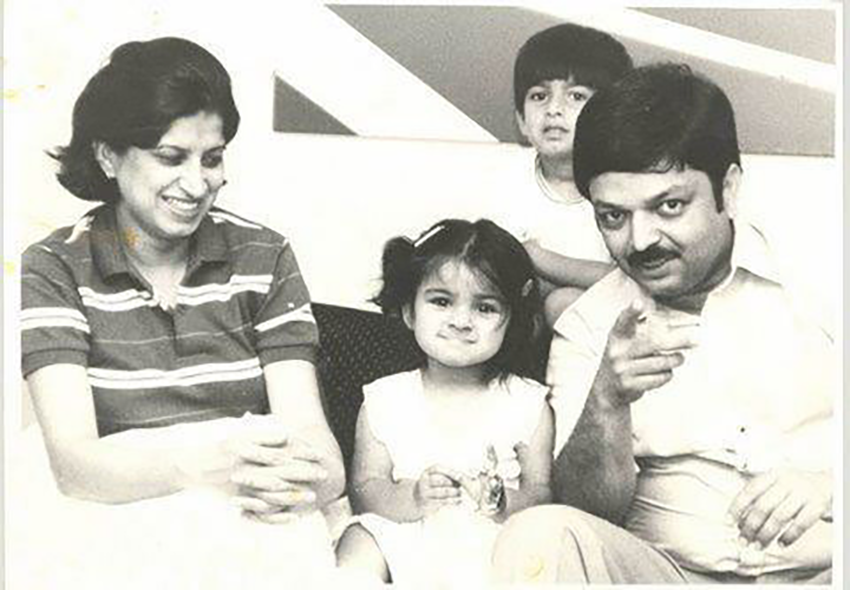 A family portrait in black and white featuring a woman, two children, and a man, all sitting together indoors.