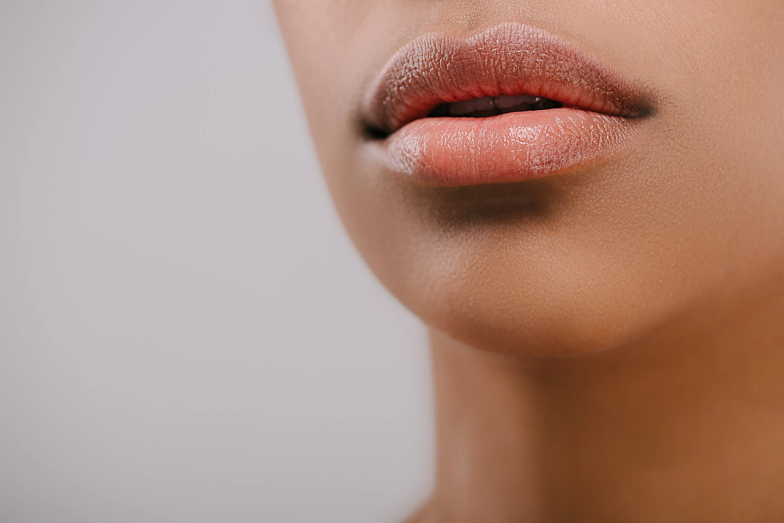 Close-up of a person's lips with natural makeup, showing smooth skin and slightly parted lips.