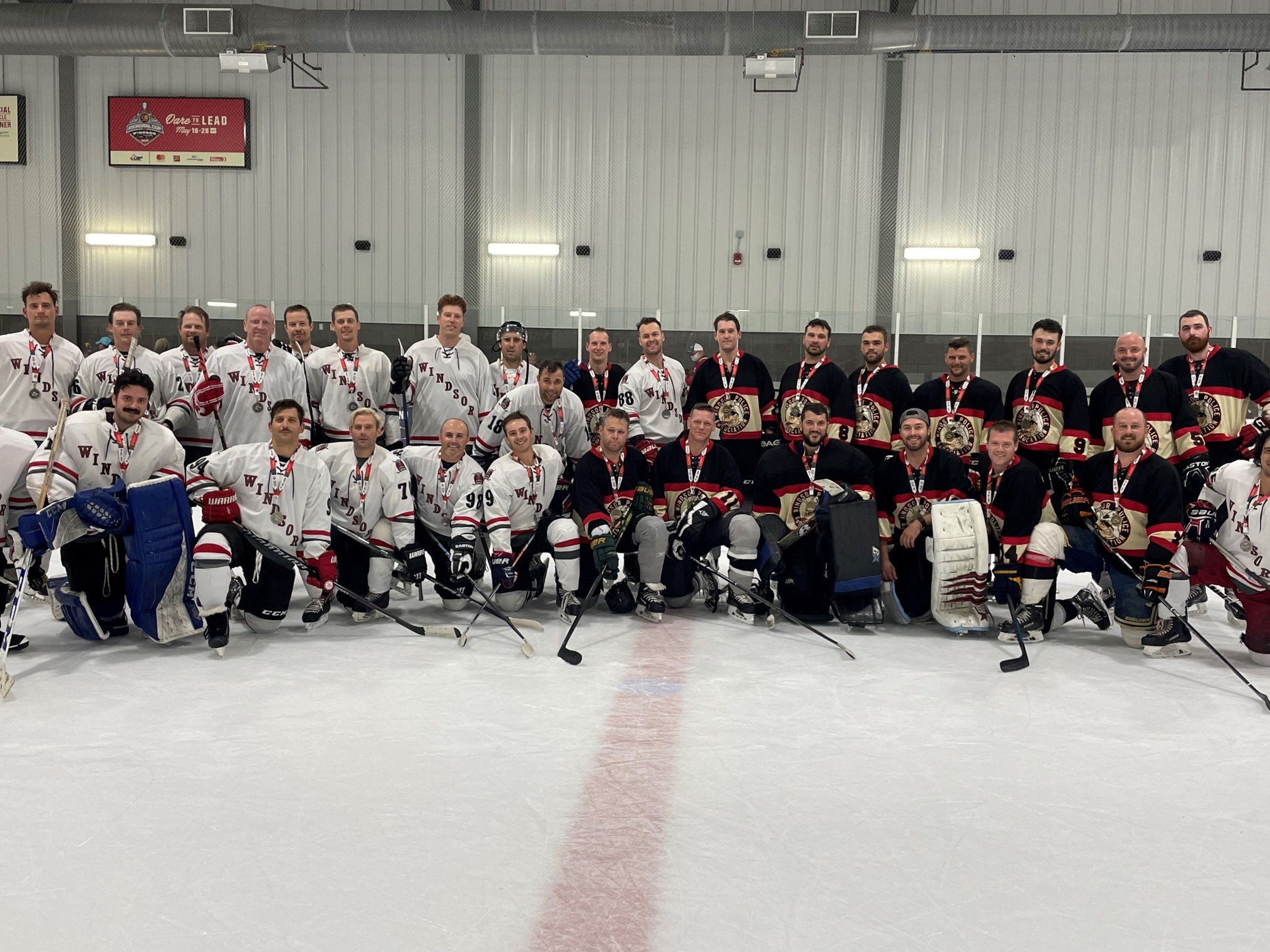 Group of ice hockey players in jerseys posing for a team photo inside an ice rink.
