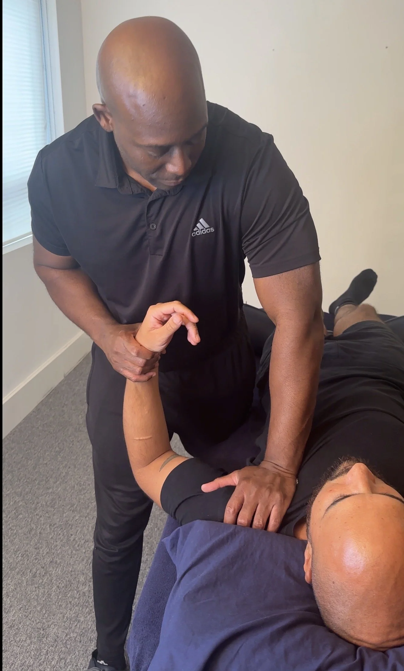 Practitioner performing an advanced manual therapy joint mobilisation technique on a client's shoulder during a Postural Remedial Reset session to improve structural alignment and upper body mobility.