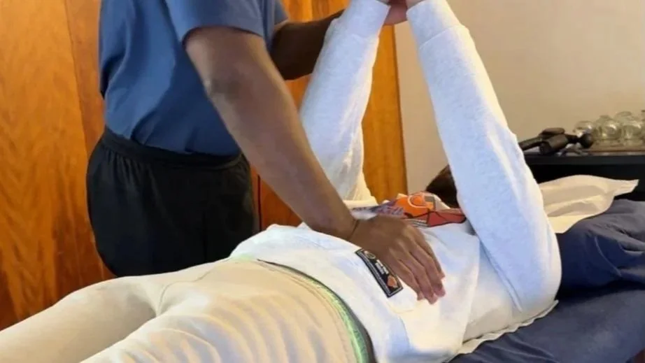 Soft tissue injury and rehabilitation therapist Nathan conducting a muscle assessment test on a patient's during a clinical injury rehabilitation treatment session..