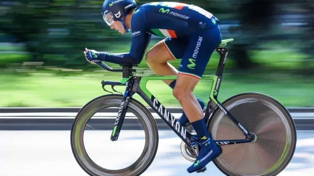 Professional Movistar cyclist in an aerodynamic time trial position on a Canyon bike, showcasing elite performance overhaul and athletic biomechanics.