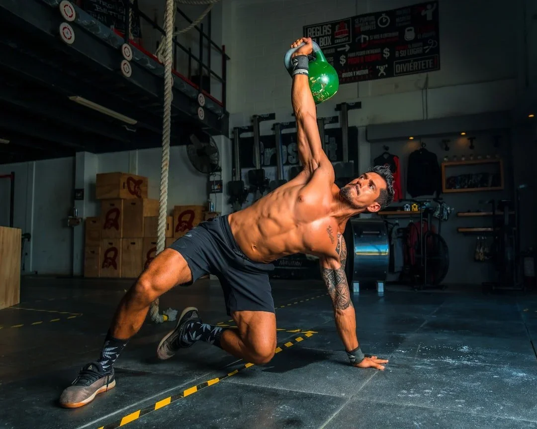 An athlete performing a kettlebell Turkish get-up in a gym. Represents the Elite Performance Overhaul at My Therapy Method, built for sports conditioning and athletic optimisation.
