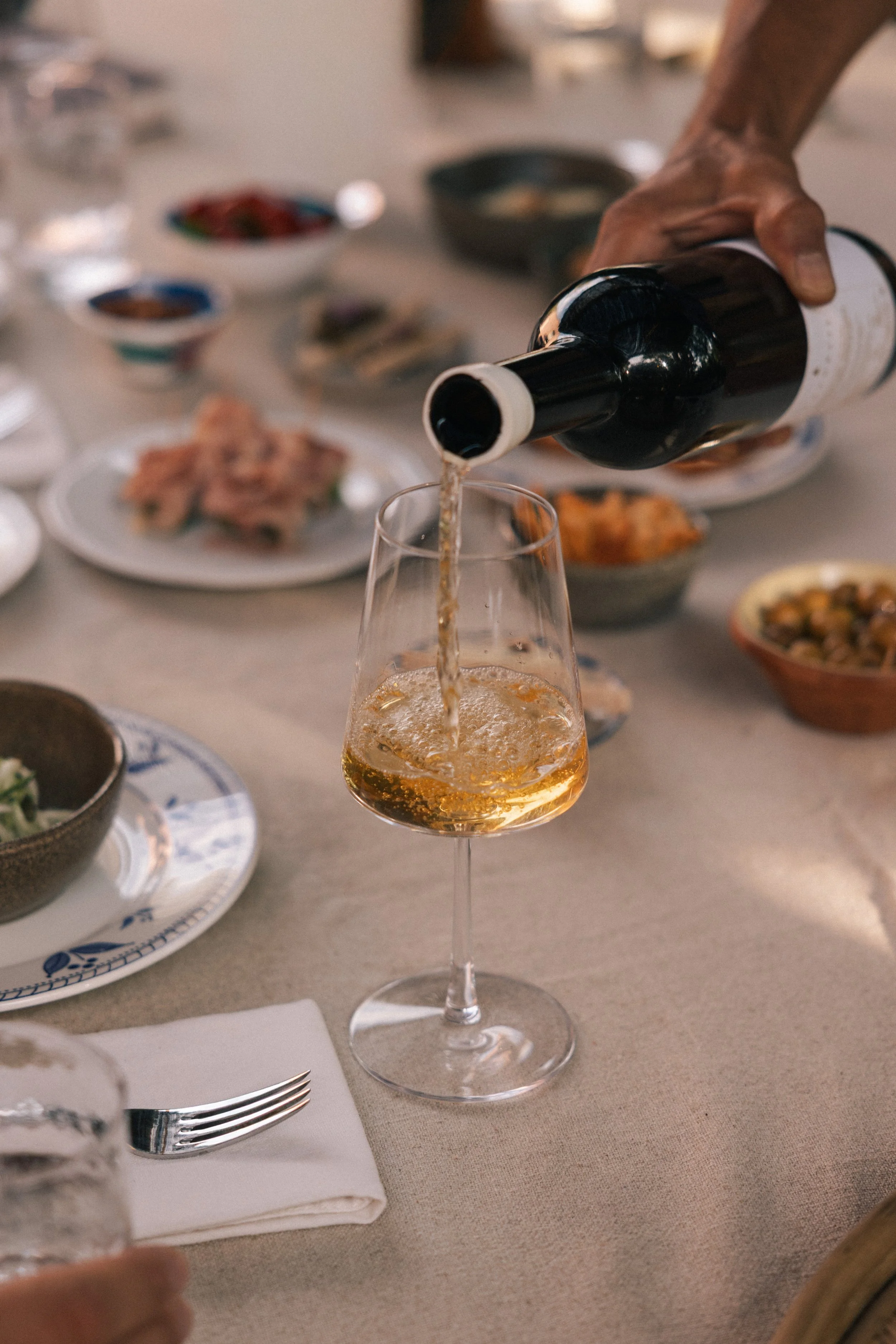 serving Anforaje white wine, at a table set with various appethizers 