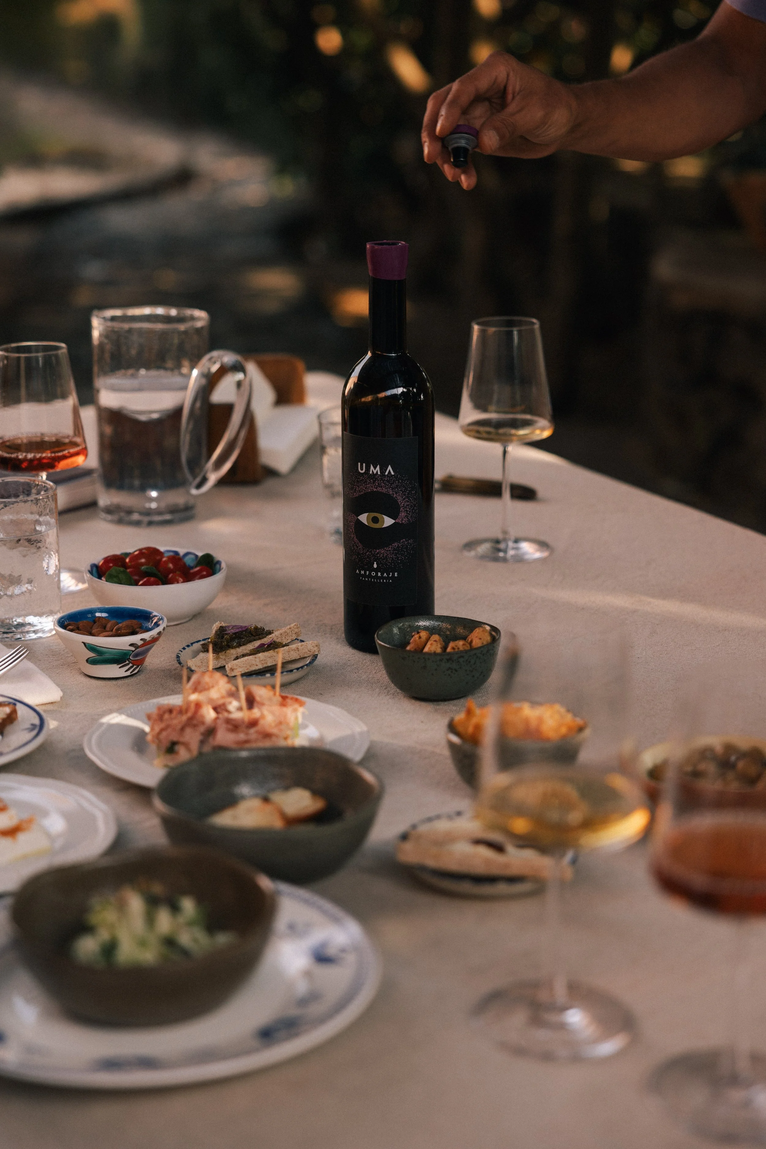 opening a bottle of Anforaje UMA on table with various appetizers