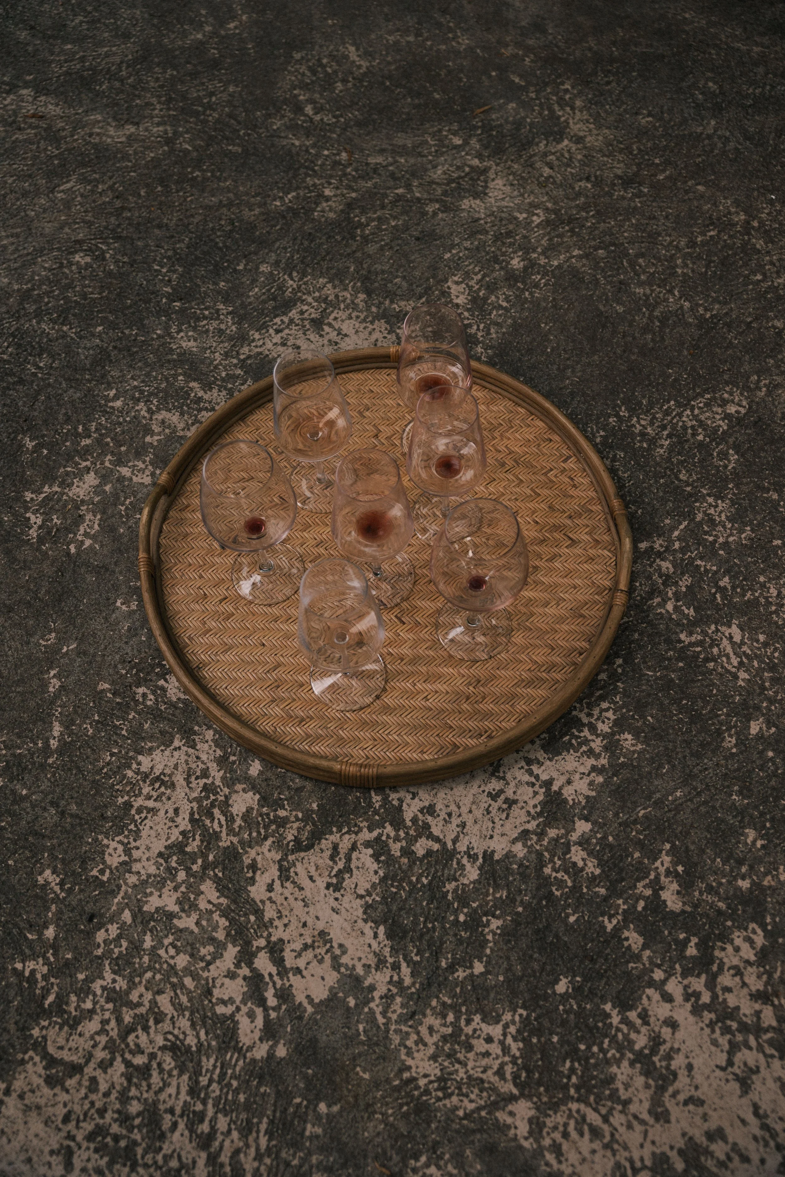 A round wicker tray with ten empty wine glasses after an Anforaje degustation